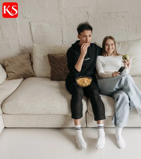 Frau schaut abends auf dem Sofa einen Film über einen Streaming-Dienst